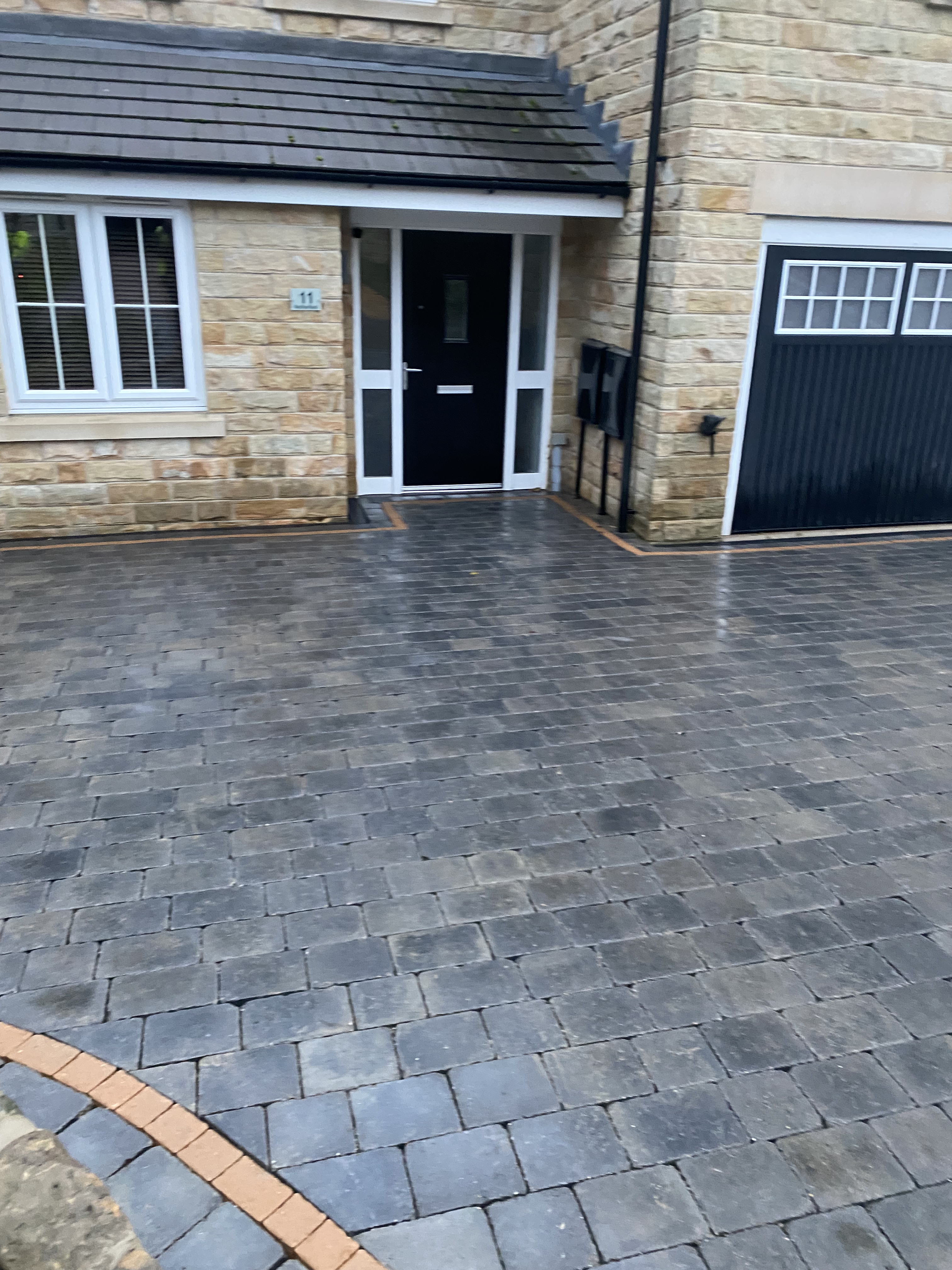 Paved driveway with stone house entrance.